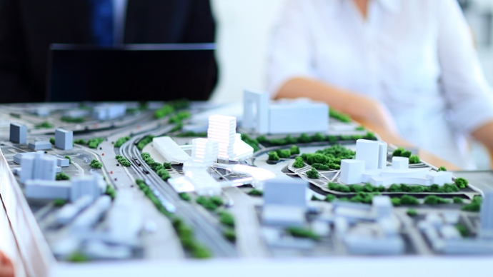 Modell einer Stadt mit weißen Häuser / Hochhäusern, Straßen, ÖPNV-Linien und Begrünung