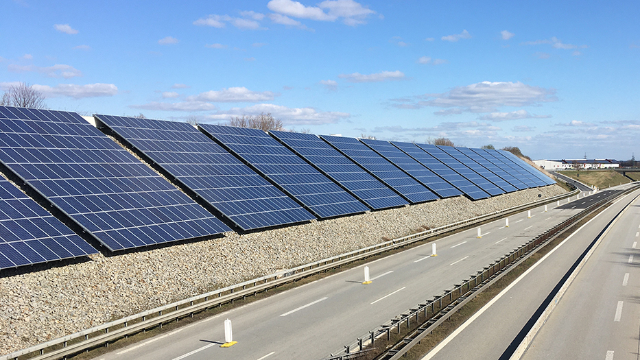 Auf einer Böschung an einer Autobahnauffahrt sind Photovoltaikanlagen aufgebaut