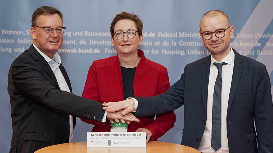 Vor der Presserückwand des BMWSB steht Bauministerin Klara Geywitz zusammen mit Tim-Oliver Müller (Rechts) und Axel Gedaschko (links). Sie drücken gemeinsam auf einen Startknopf
