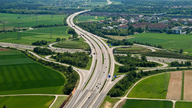 Blick aus der Vogelperspektive auf eine Autobahn mit Anschlussstelle in der Nähe eines Ortes