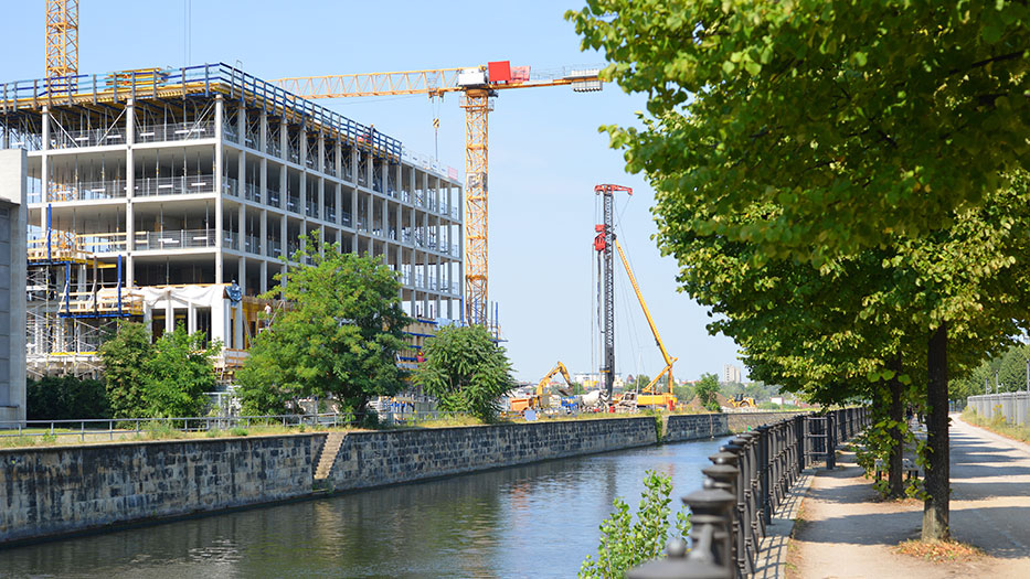 Rohbau Baustelle Berlin mit Baukränen und Ufer